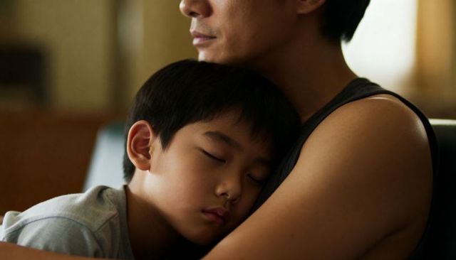 Father cradling sleeping son on sofa holding tender nighttime bonding moment parenting comfort