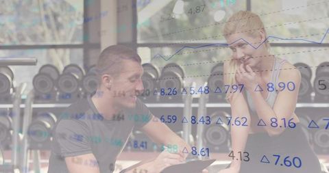 Trainer reviewing client progress with clipboard and performance graphs in modern gym