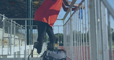Teen paralympic athlete balancing on carbon-fiber running blades in outdoor stadium stands