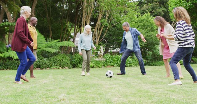 Image of happy diverse female and male senior friends playing soccer in garden. retirement lifestyle, spending quality time with friends.