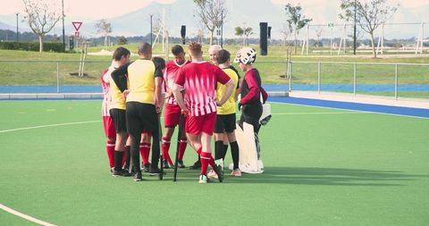 Field hockey team huddling on outdoor turf pitch