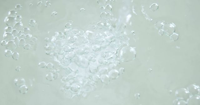 Bubbles rise dynamically through clear water, creating a sense of movement and purity. This close-up shot captures the effervescence and clarity often associated with freshness and cleanliness.