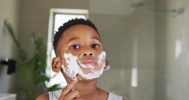 Image of african american boy shaving in bathroom. Childhood, spending free time at home concept.