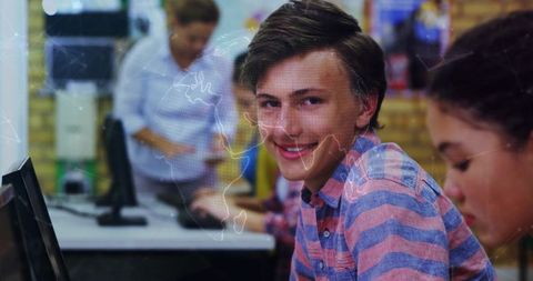 Smiling Teen Boy Engaging with Technology in Classroom Setting