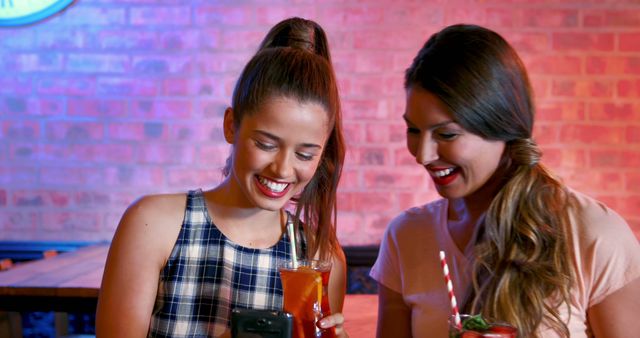 Friends Enjoying Drinks and Looking at Smartphone in Bar - Download Free Stock Images Pikwizard.com