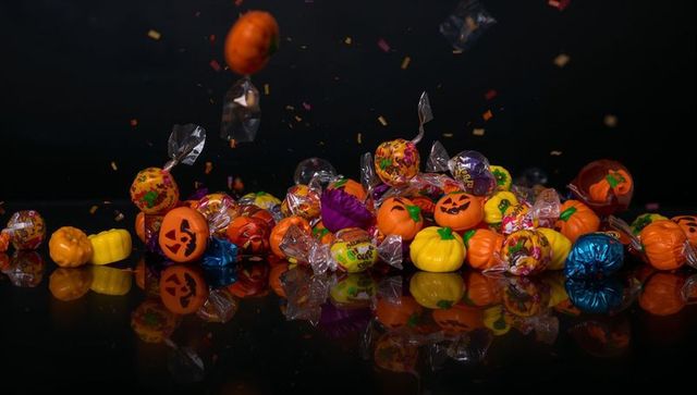 Assorted Halloween Candies Reflecting on Glossy Black Surface