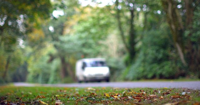 Van driving on a forest road during fall with motion blur, surrounded by dense trees and foliage. Useful for concepts of travel, autumn journeys, transportation, and nature.