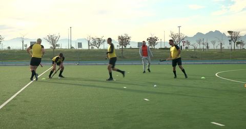 Male Hockey Team Practicing Drills on Synthetic Turf at Dusk