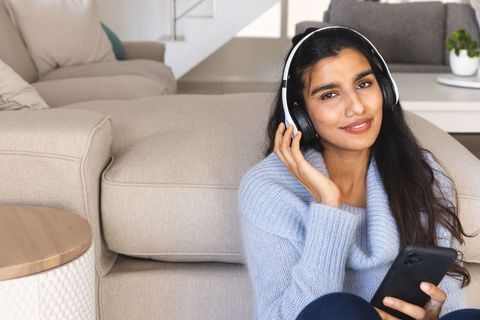 Woman Relaxing with Headphones Using Smartphone in Cozy Living Room