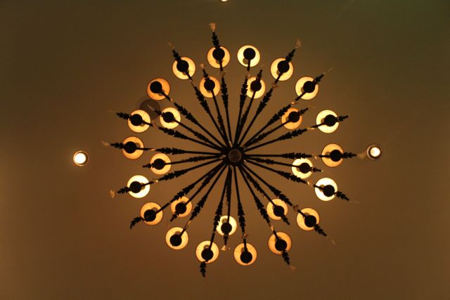 Ornate chandelier viewed from below, featuring intricate details and warm bulb lighting. Suitable for interior design inspirations, home decor blogs, and articles on vintage or classic aesthetic styles.