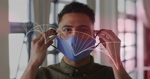 Young man adjusting reusable face mask with airflow visualization, indoor health safety