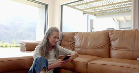 Mature Woman Relaxing with Smartphone in Modern Living Room