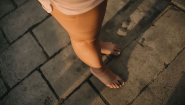 Sunlit bare feet on stone pavers with pedicure, golden hour shadows, casual summer vibes