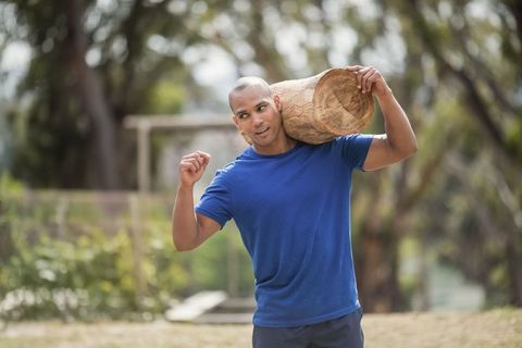 Athletic Man Carrying Log in Outdoor Fitness Activity