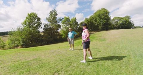 Senior couple enjoying golf on sunny day outdoors