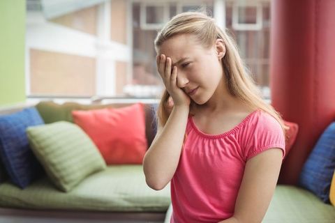 Teenage girl experiencing aches on cozy sofa