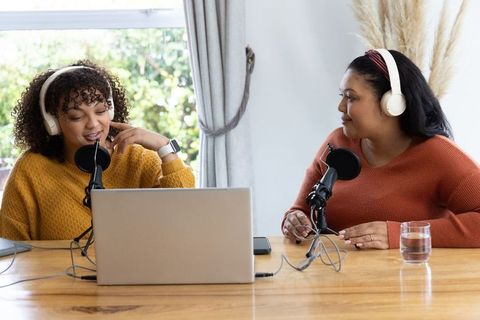 African American cohosts recording podcast in home studio with laptop and mic setup