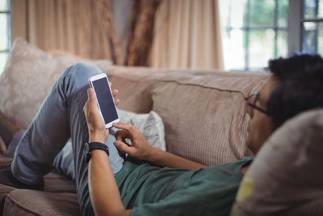 Man using mobile phone in living room at home