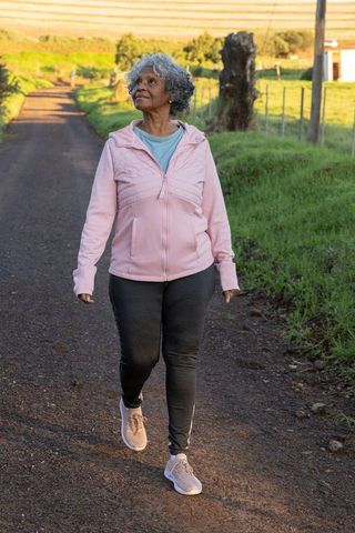 Senior woman enjoying outdoor walk on rural pathway