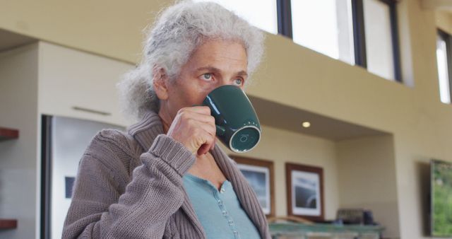 Senior biracial woman holding mug and drinking. retirement and senior lifestyle, spending time alone at home.