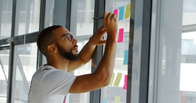 Focused Professional Writing on Sticky Notes in Modern Office - Download Free Stock Images Pikwizard.com