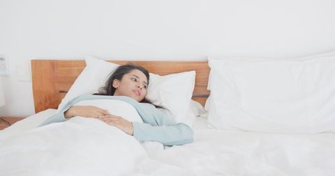 Serene woman resting on bed with minimalist white backdrop