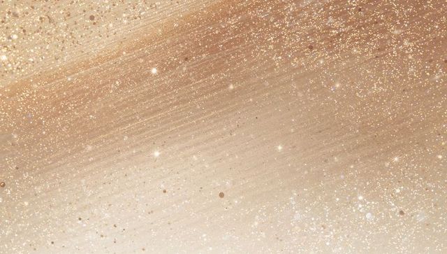 Shimmering gold-beige glitter brushstroke backdrop with sparkling bokeh and star glints