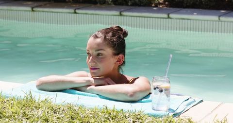 Woman relaxing poolside with refreshing fruit infused water