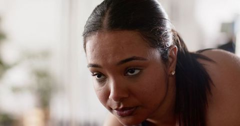 Woman leaning forward focusing on task at home with stud earrings and soft backlight
