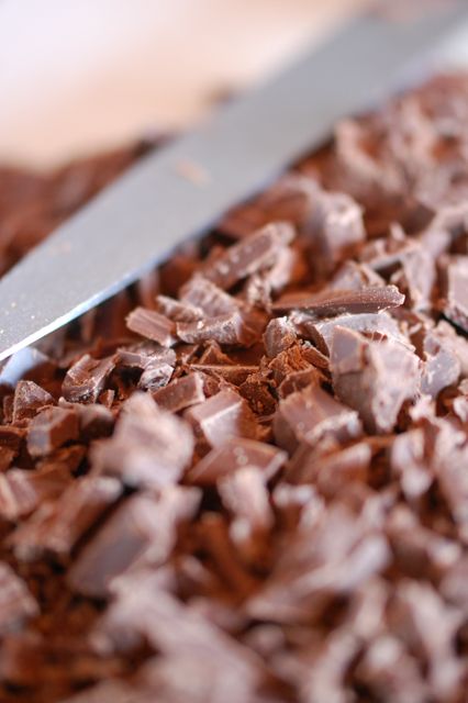 Chopped chocolate with a knife, close-up. Perfect for illustrating scenes related to baking, cooking, or dessert preparation. Ideal for use in blogs, recipe books, culinary websites, and promotional materials for chocolate products or cooking tools.
