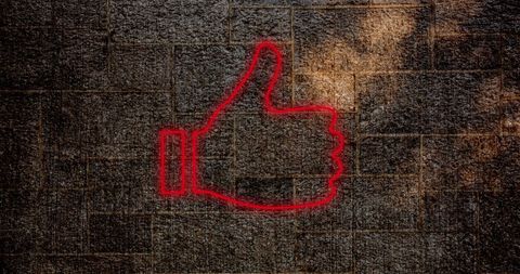 Neon Thumbs Up Icon Glowing Against Brick Wall