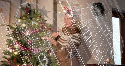 Young woman decorating christmas tree with augmented reality interface in cozy home