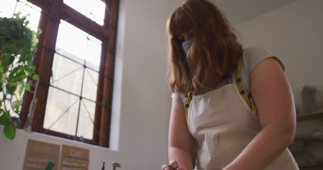 Female Artisan Working in Craft Workshop Wearing Apron and Face Mask - Download Free Stock Images Pikwizard.com