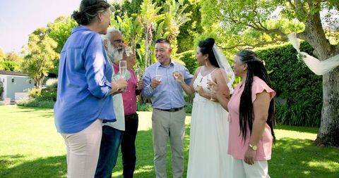 senior bride and groom toast with friends in sunny garden celebration - Download Free Stock Images Pikwizard.com