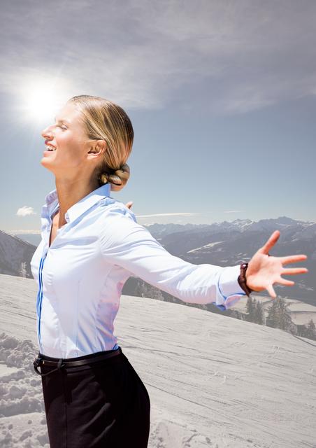 Blonde businesswoman with arms outstretched stands on snow-covered mountain peak, basking in sunlight and blue sky. Expressions suggest triumph, freedom, and personal success. Ideal for themes related to business success, work-life balance, achieving goals, corporate retreats, and personal growth in natural environments.