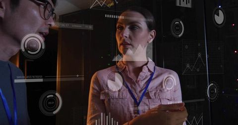 It engineers collaborating in server room with holographic analytics dashboard and metrics