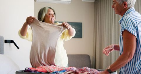 Senior Lesbian Couple Packing Suitcase for Vacation