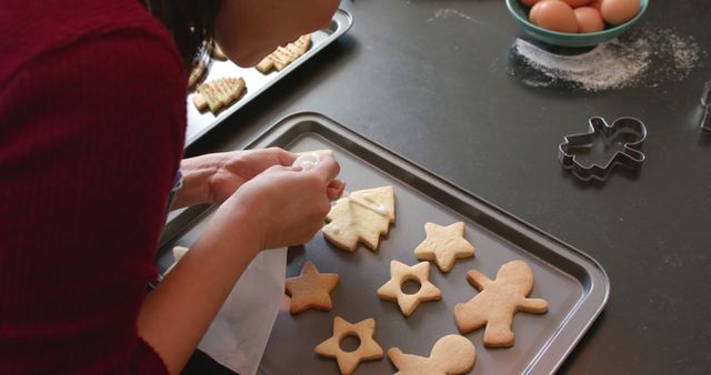 Person Decorating Christmas Cookies on Baking Sheet in Kitchen - Download Free Stock Images Pikwizard.com