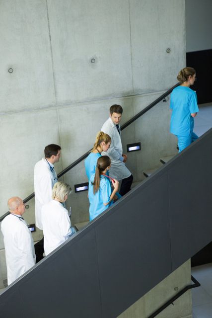 Group of doctors and surgeons interacting with each other on staircase in hospital