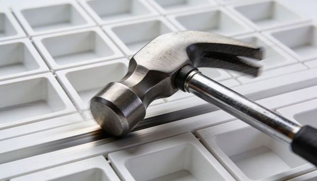 Claw hammer lying diagonally on white grid panel showing scratches on chrome handle