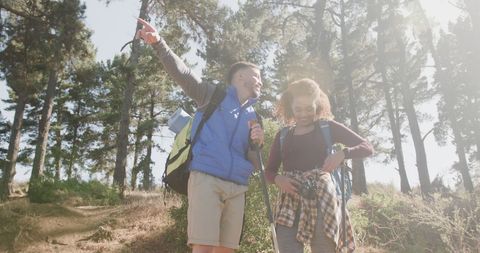 Joyful Couple Hiking in Sunny Forest with Backpacks
