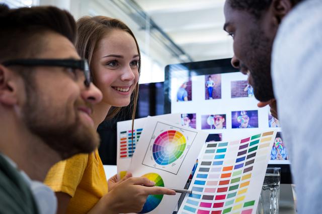Group of graphic designers choosing color from color chart in office