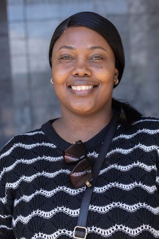 Confident smiling african woman wearing knit sweater and sunglasses urban headshot