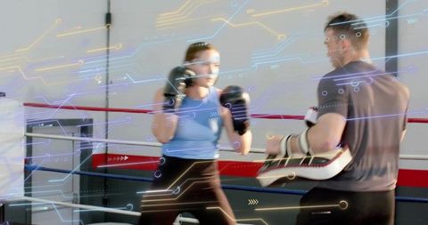 Female boxer training with coach holding focus mitts in ring with circuit tech overlay