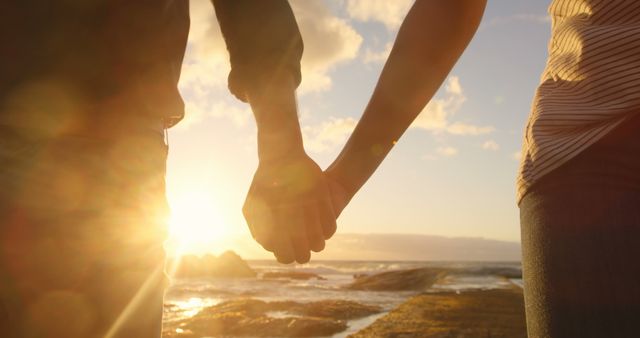 Diverse couple holding hands at sunset, with copy space. Their romantic moment captures the essence of a beachside connection.