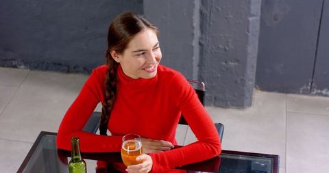 Woman in red sweater relaxing with beer at office workspace