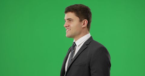 Confident Businessman in Suit Smiling on Green Background