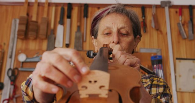 Craftsman Adjusting Strings on Violin in Workshop - Download Free Stock Images Pikwizard.com