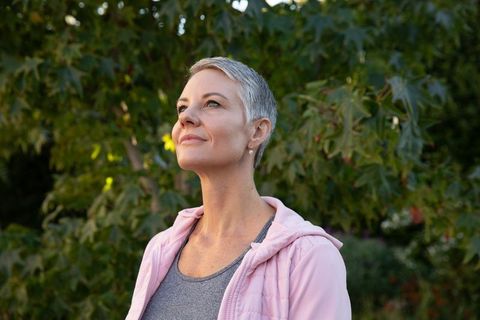 Woman Enjoying Tranquil Moment in Sunlit Backyard