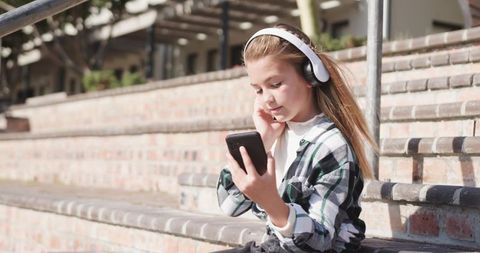 Young Girl Listening to Music on Smartphone Outdoors